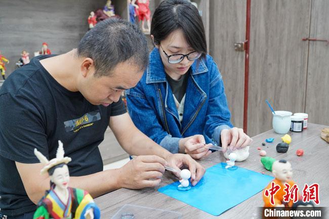 <a target='_blank'  data-cke-saved- >中新社</a>記者(右)現(xiàn)場體驗面塑制作過程?！￡悹帍?攝