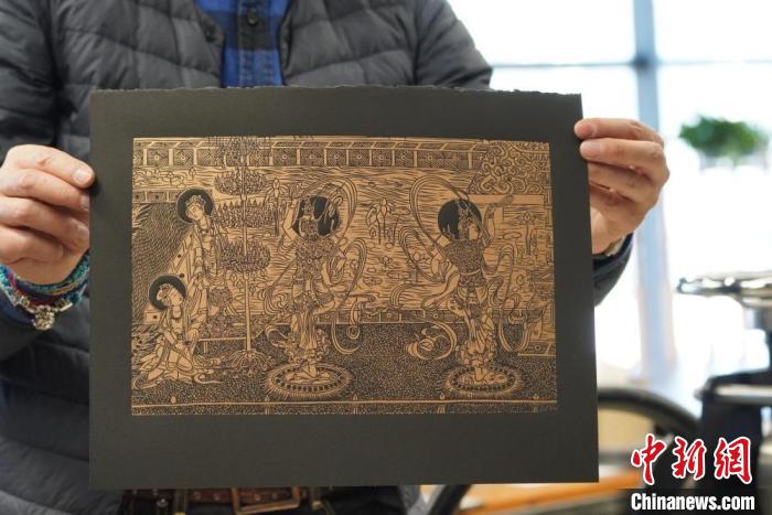 圖為手工書(shū)藝人展示敦煌雕版壁畫(huà)印刷品。　九美旦增 　攝