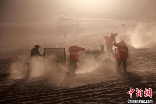 圖為敦煌市鳴沙山月牙泉景區(qū)“駱駝保姆”清理駱駝糞便?！垥粤?攝