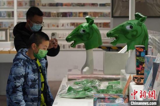 圖為“神馬來(lái)了”銅奔馬頭套吸引參觀者駐足?！【琶赖┰?攝