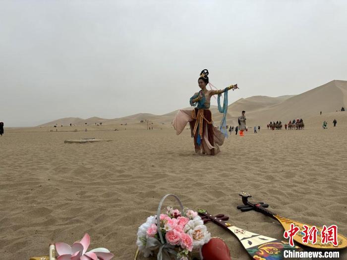 圖為2023年4月底，敦煌大漠“逐舞者”奧楠在鳴沙山月牙泉景區(qū)視頻直播敦煌舞?！●T志軍 攝