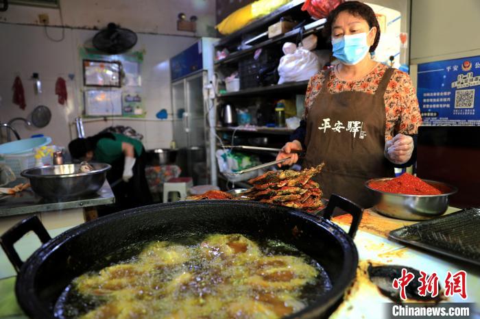 圖為平安驛·河湟民俗文化體驗(yàn)地內(nèi)的商戶炸干板魚?！⊙Φ?攝