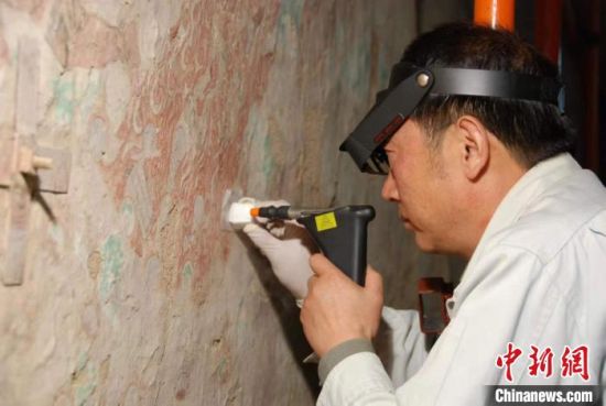 敦煌研究院研究員樊再軒進(jìn)行壁畫修復(fù)。(資料圖)張?jiān)莆?攝