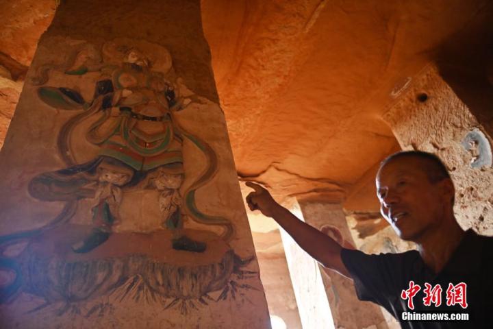 7月15日，甘肅省平?jīng)鍪袥艽h百里石窟長廊羅漢洞石窟內(nèi)，該窟文保員郭建平介紹窟內(nèi)石刻彩繪壁畫。郭建平家中三代人曾自發(fā)保護(hù)羅漢洞石窟。羅漢洞石窟遺存40余個(gè)窟龕，以北魏至清代風(fēng)格為主。中新社記者 李亞龍 攝</p>
<p>